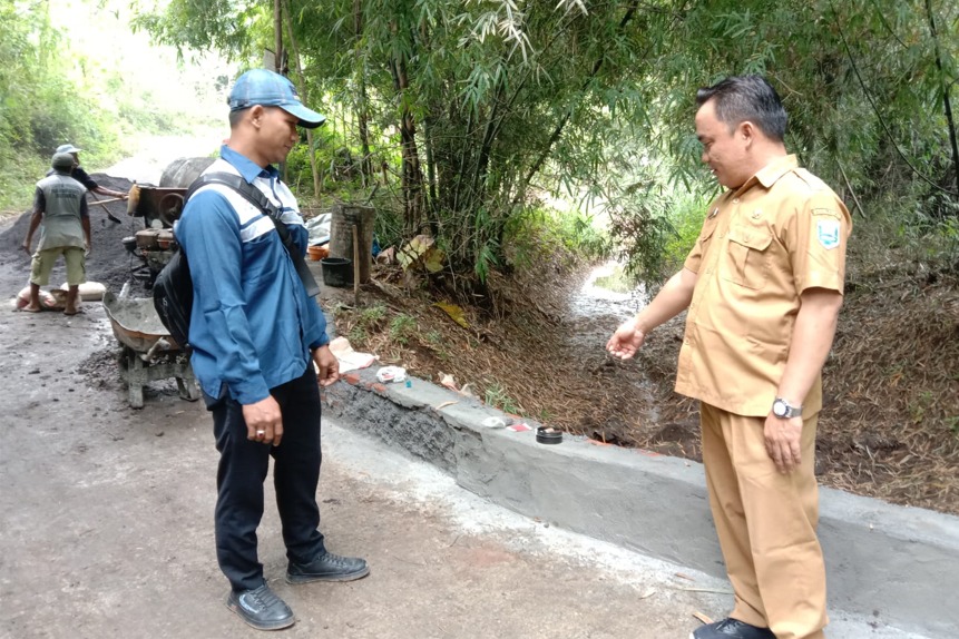 PEMBANGUNAN: Kepala Desa Tigasan Kulon Suhin Setiawan (pakai baju dinas) meninjau proses finishing jembatan limpas di Dusun Curahwindu