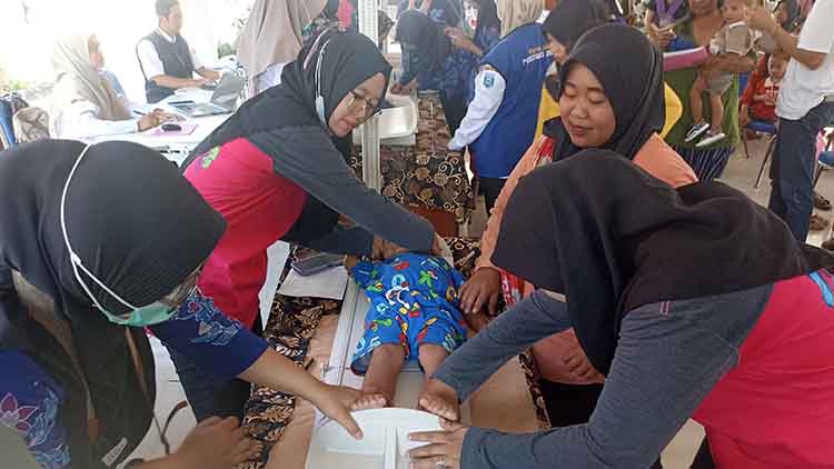 PENIMBANGAN: Petugas kesehatan menimbang berat badan balita sebagai bagian dari skrining.