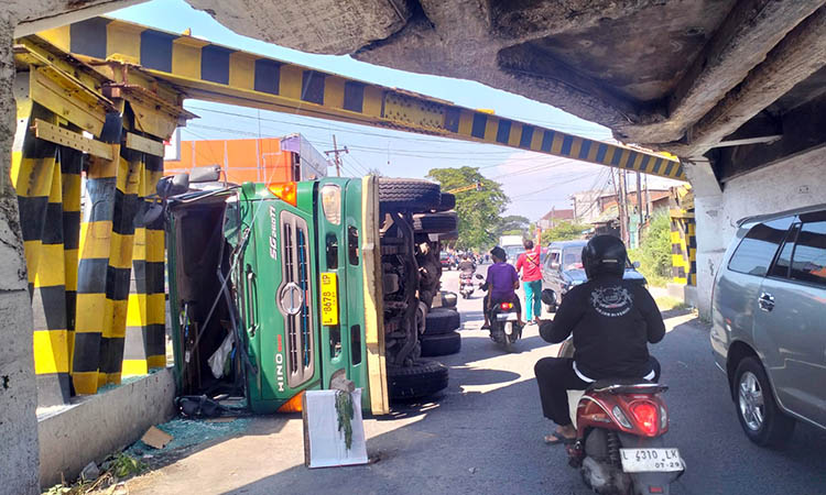TUTUPI JALAN: Truk kontainer pengangkut minuman kemasan yang terguling. Kendaraan tersebut menutupi separoh jalan, sehingga sebagian arus dialihkan.