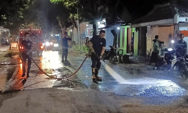 PENYEMPROTAN: Petugas Damkar dan BPBD Kota Pasuruan saat melakukan pembersihan Jalan Imam Bonjol. Hal ini dilakukan, untuk mencegah korban berjatuhan, usai jalan setempat ketumpahan solar.