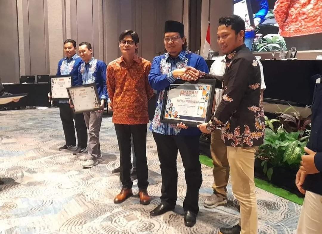 PENGHARGAAN: Radfan Faisal saat menerima penghargaan kategori Sosialisasi dan Keterbukaan Informasi Publik yang diterima dari KPU Provinsi Jawa Timur serta Komisi Informasi Jawa Timur.