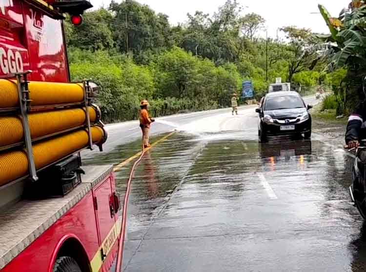 DIBERSIHKAN: Tim Damkar Satpol PP Kabupaten Probolinggo, membersihkan tumpahan solar di Jalur Pantura, Pantai Bentar, Jumat (27/6).