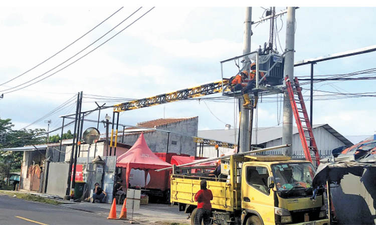 PASANG: Petugas PLN ULP Probolinggo memasang trafo sisipan di Jalan Anggrek, Kelurahan Pilang, Kecamatan Kademangan, Minggu (29/6).