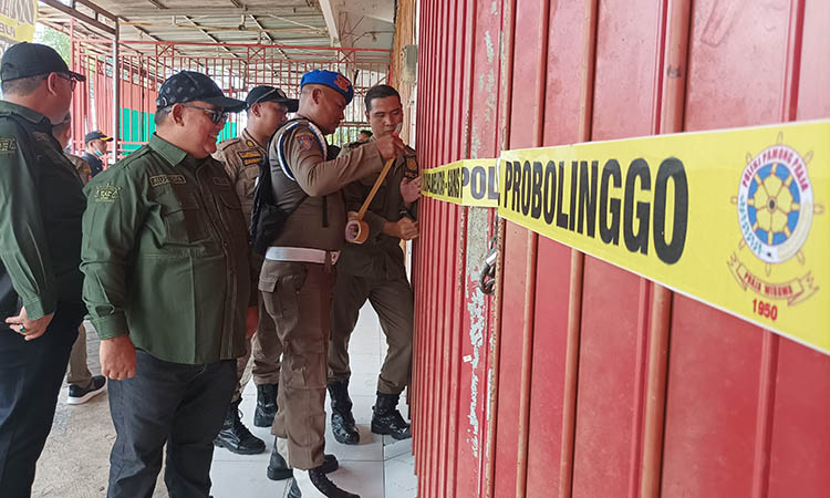 DISEGEL: Satgas miras dari berbagai unsur saat menutup dua ruko dengan memasang segel dan menggembok pintu ruko di Green Garden, Kelurahan Sumberlele, Kraksaan,