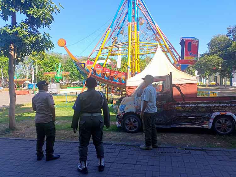 TAK BERIZIN: Anggota Satpol PP Kota Probolinggo memantau sejumlah wahana permaian di Alun-alun Kota Probolinggo, yang sejatinya harus sudah dibongkar.