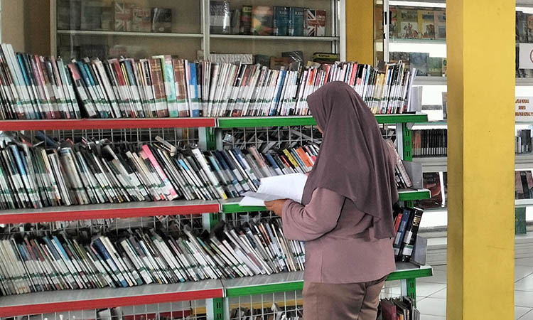 MEMBACA: Seorang pengunjung Perpustakaan Pandaan tengah asik membaca buku yang disediakan. Meski bangunan perpustakaan setempat butuh sentuhan, perbaikan belum bisa dilakukan.