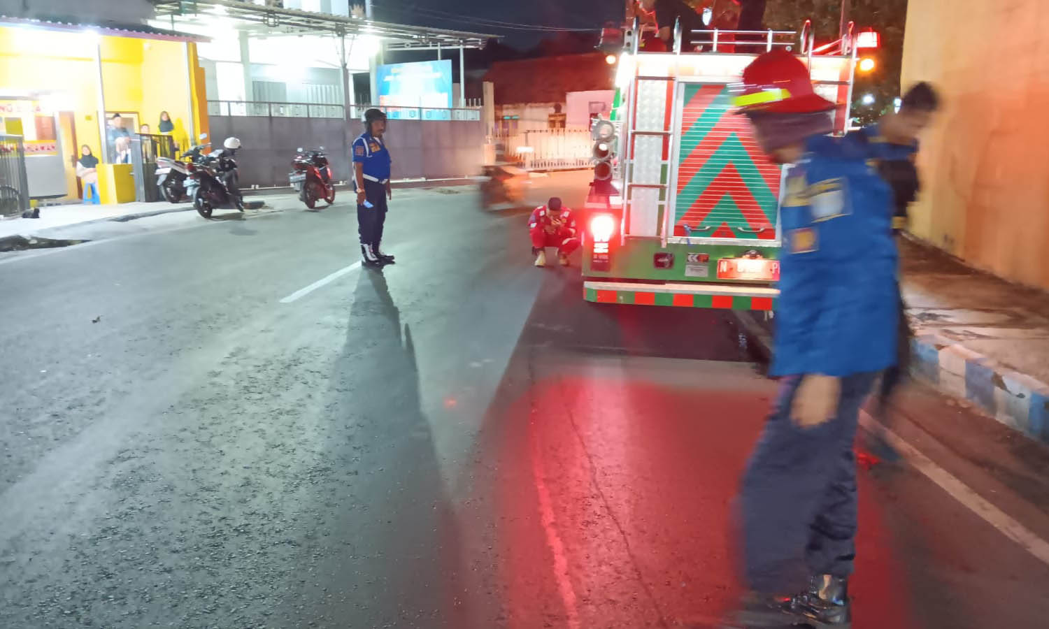 SEMPROT: Petugas Damkar Satpol PP Kota Probolinggo saat melakukan penyemprotan tumpahan solar di Jalan Pahlawan, Kelurahan Jati, Kecamatan Mayangan, Kota Probolinggo, Kamis (17/7) malam