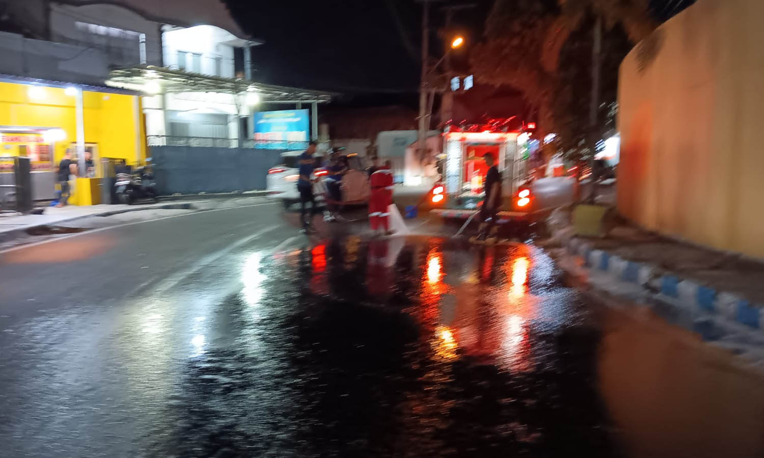 SEMPROT: Petugas Damkar Satpol PP Kota Probolinggo saat melakukan penyemprotan tumpahan solar di Jalan Pahlawan, Kelurahan Jati, Kecamatan Mayangan, Kota Probolinggo, Kamis (17/7) malam