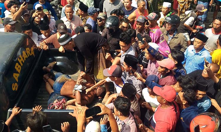 DIAMUK MASSA: Salah satu pelaku curanmor di Masjid Baitul Anwar, Desa Sentul, Kecamatan Gading, Probolinggo diamankan warga ke mobil patroli Polsek Gading.