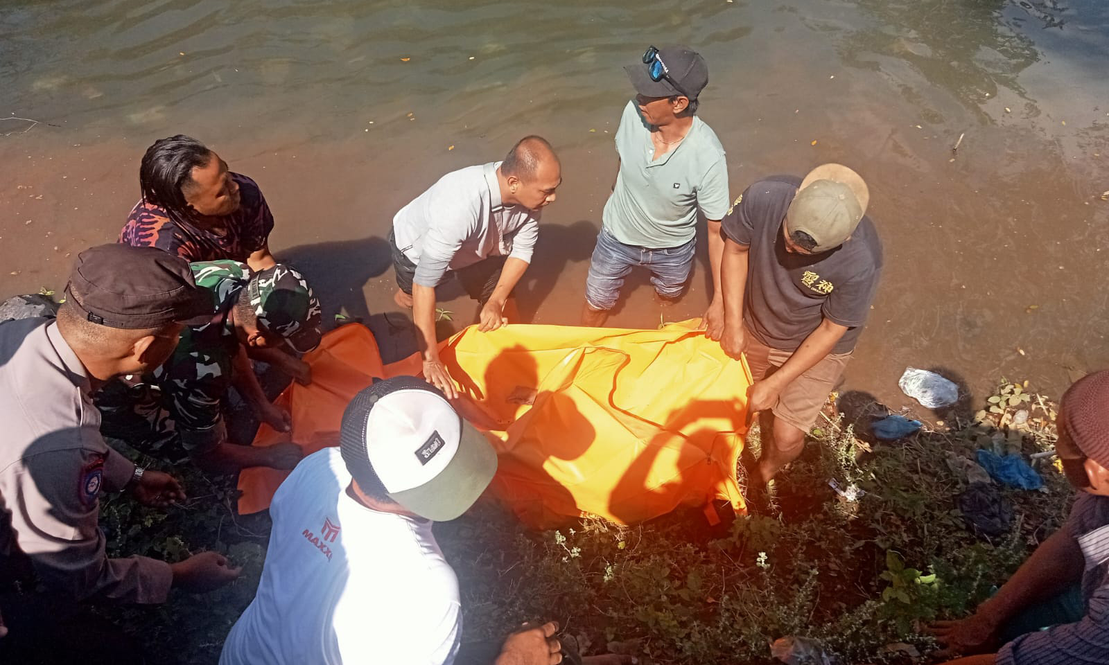 DIEVAKUASI: Anggota Polsek Maron bersama warga mengevakuasi jenazah korban dari Sungai Pekalen, Senin (21/7).