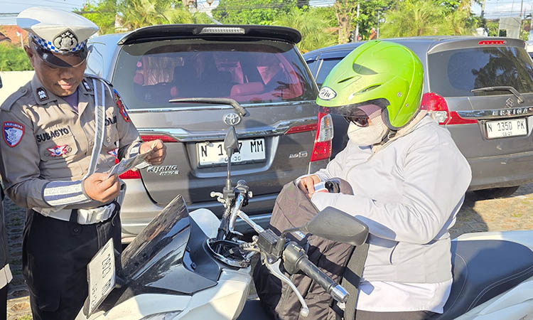 DIPERIKSA: Petugas mengecek kelengkapan surat-surat kendaraan pengendara motor yang melintas di ruas jalan Pantura.