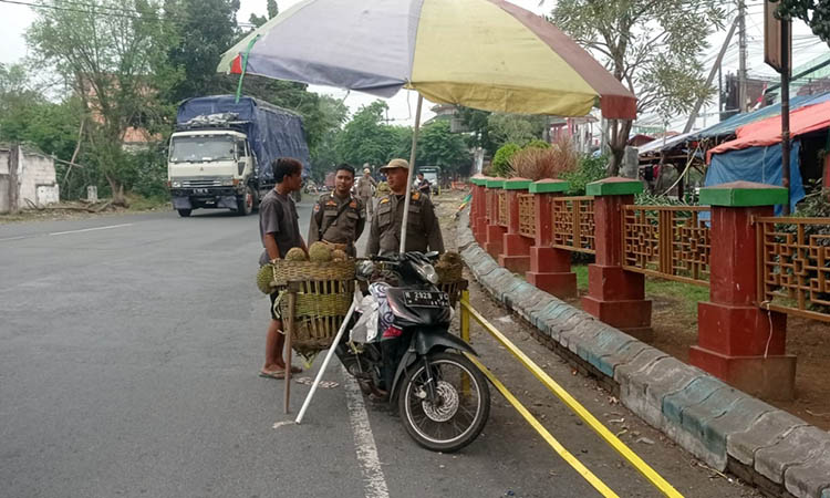 TEGUR: Petugas Satpol PP Kota Pasuruan saat memberikan teguran kepada PKL yang berjualan di tepi jalan depan Pasar Wisata Cheng Hoo Pandaan.