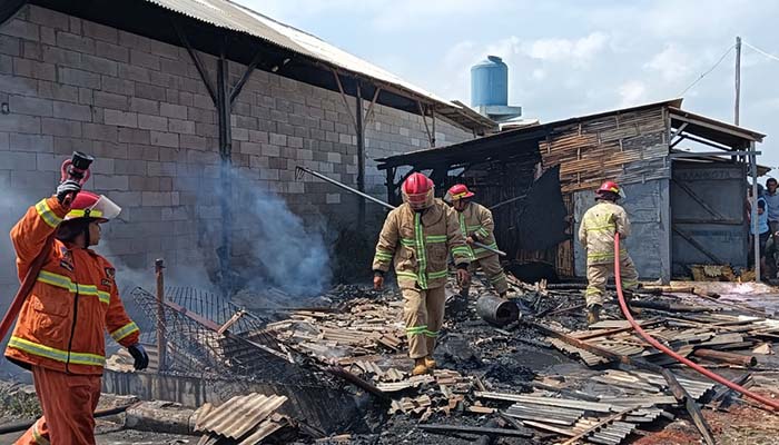 AMUK SI JAGO MERAH: Petugas damkar saat berupaya memadamkan gudang bajong yang terbakar di TPI Mayangan, Probolinggo.