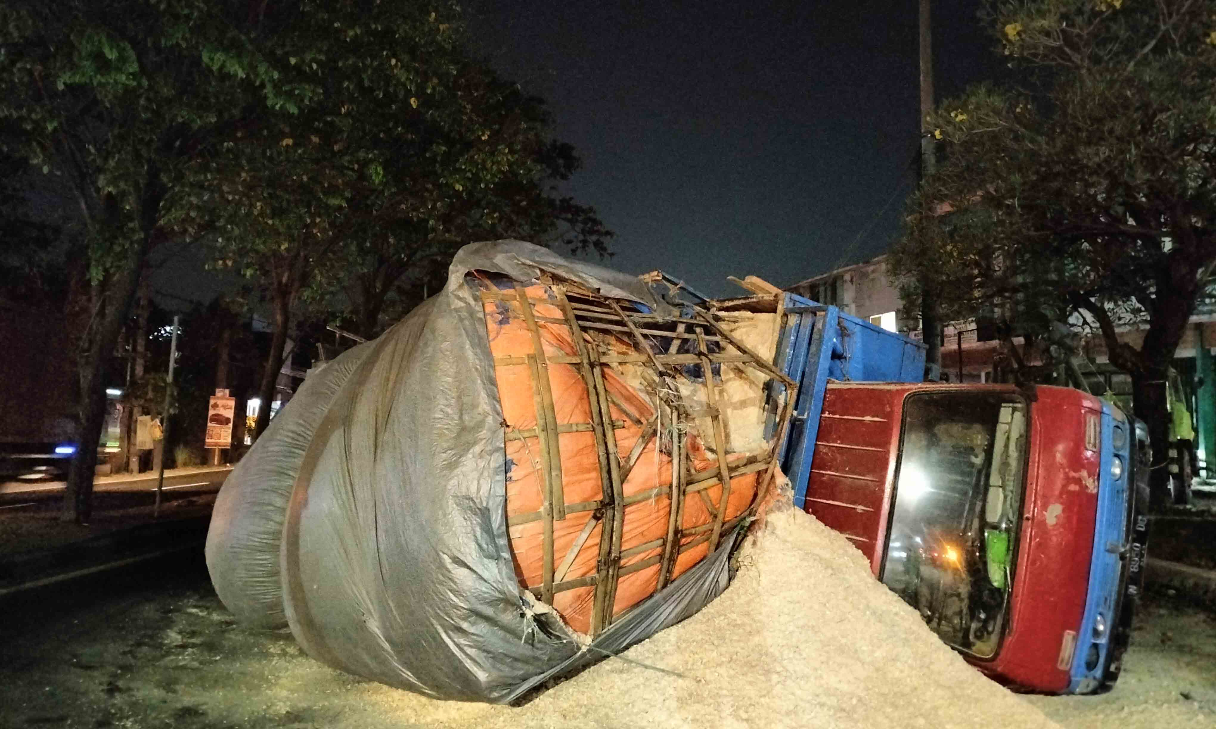 GULING: Truk muatan serbuk kayu yang terguling di By Pass Pandaan. Parahnya, ada mobil Avanza yang tertimpa muatan.