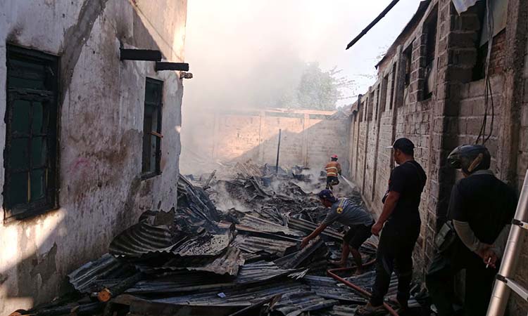 HANGUS: Petugas dibantu warga saat melakukan pembasahan di rumah dan gudang milik bos mebel di Winongan, Pasuruan.