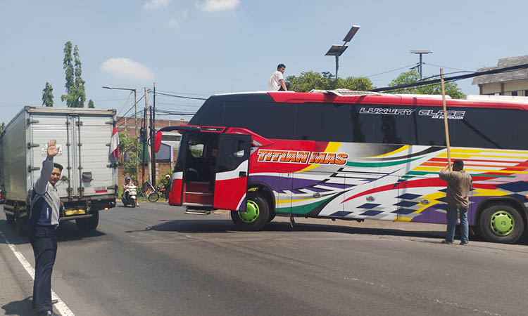 PAKAI GALAH: Petugas di Terminal Untung Suropati Blandongan menyenggek kabel internet yang menggantung di gerbang terminal dan mengganggu bus yang akan