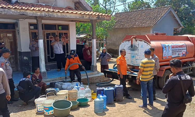 KERJASAMA: Personelp BPBD bersama kepolisian suplai air ke warga kesulitan air bersih di Tiris pada Senin (11/8) siang.