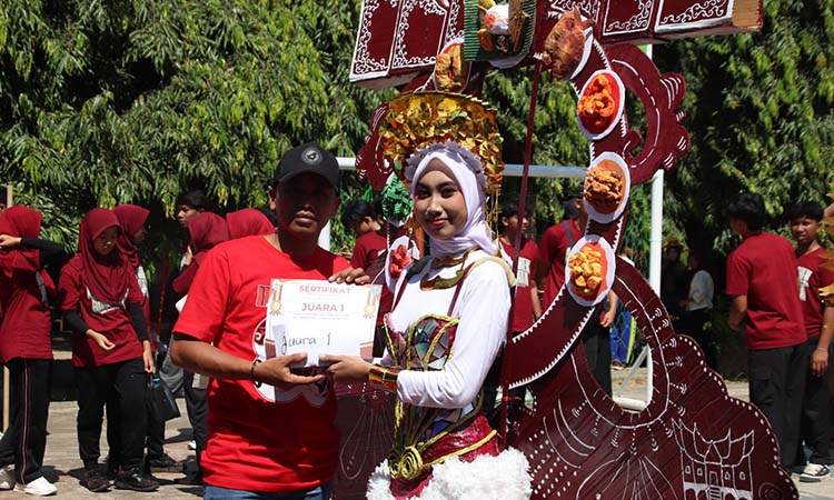 TERBAIK: Wakil Kepala (Waka) Humas Muhammad Zaiful Bahri, saat menyerahkan penghargaan kepada Juara I  maskot dari kelas XII C.