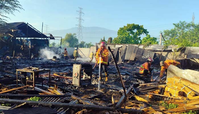 Petugas damkar saat melakukan pembasahan di puing-puing gudang mebel yang terbakar,