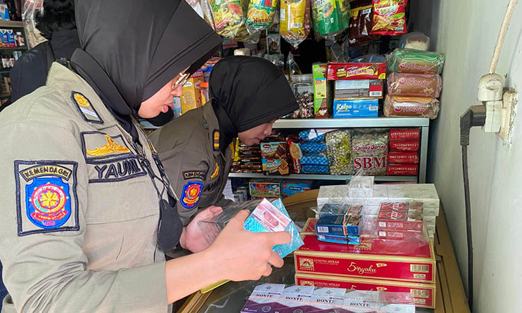 PERIKSA: Petugas Satpol PP Kabupaten Pasuruan saat memeriksa rokok-rokok yang diduga ilegal lantaran tak disertai dengan cukai.