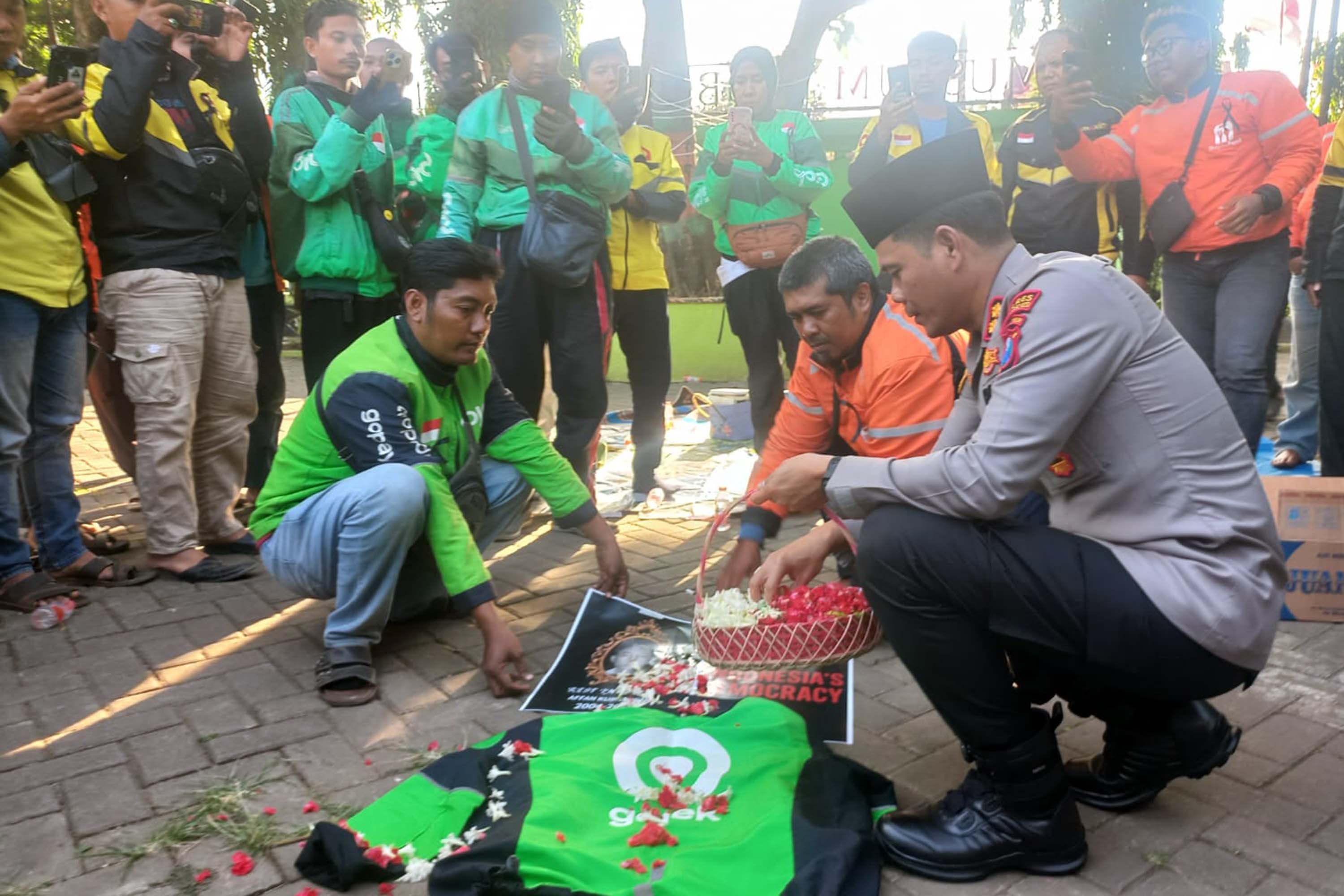 KIRIM DOA: Puluhan ojek online dan Kapolres Probolinggo Kota saat menabur bunga pada poster Affan dan jaket ojol di area Museum Probolinggo.