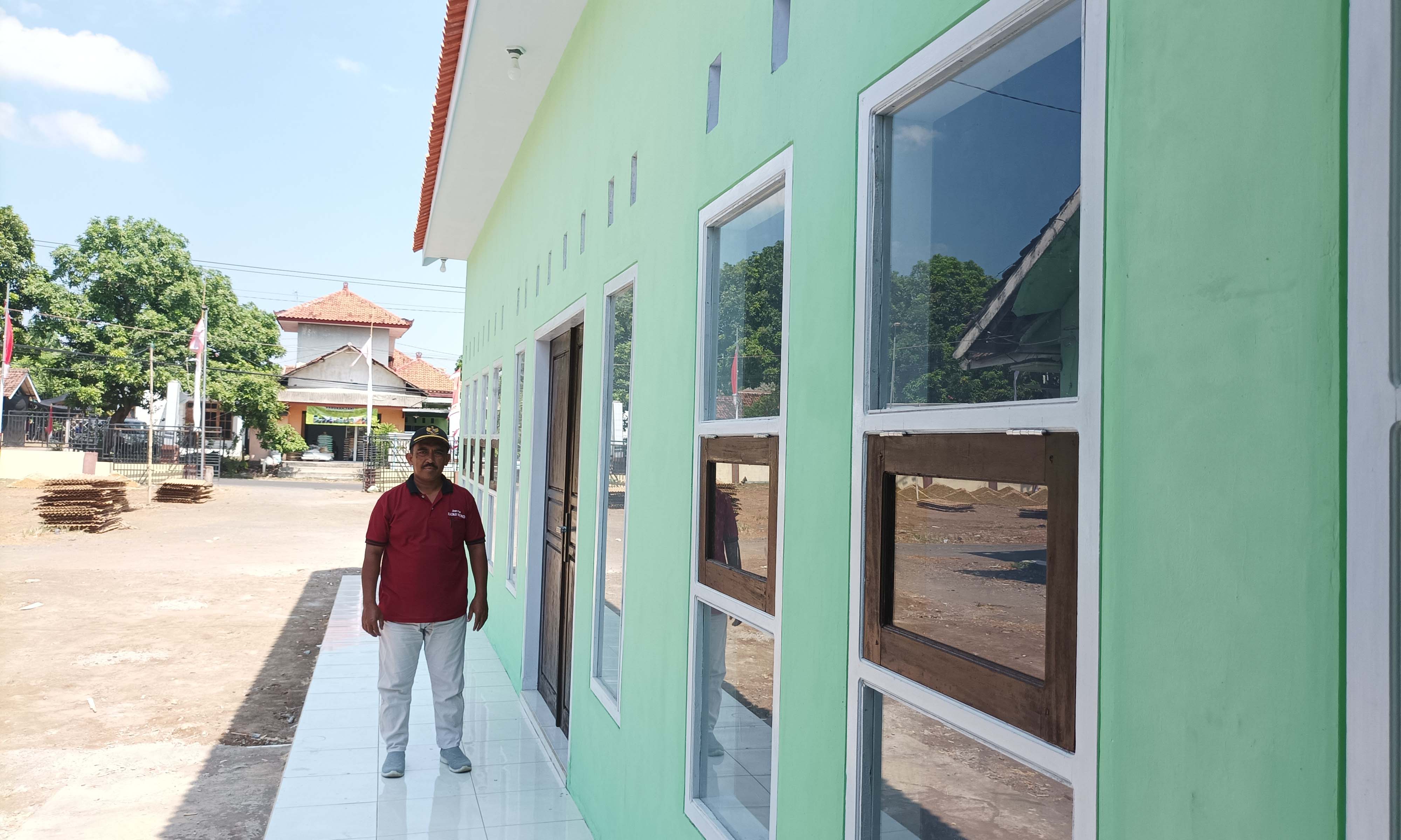 LEBIH BAIK: Bendahara Desa Seboro Purwadi berada di depan gedung pelayanan desa yang baru dibangun.