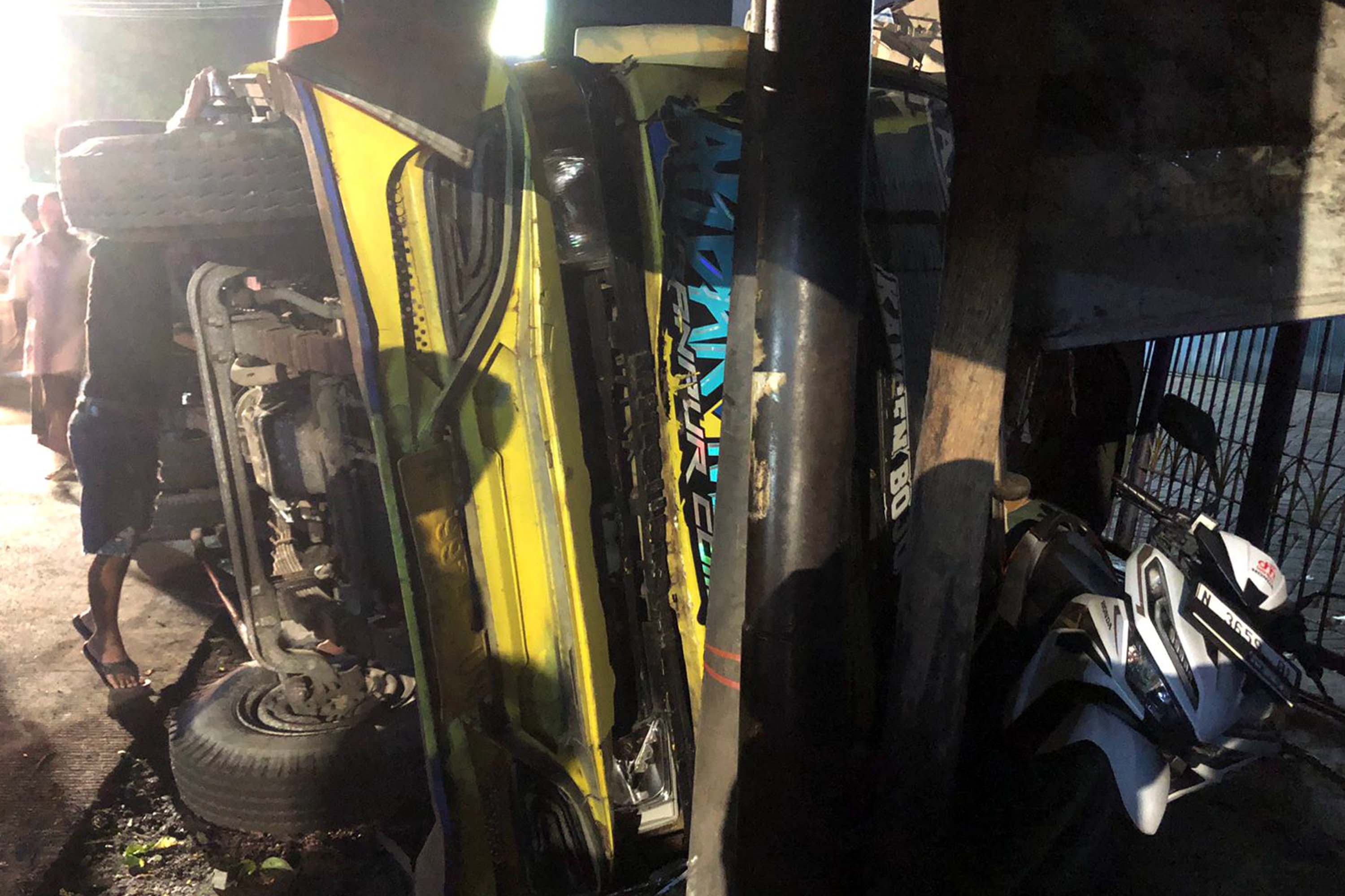 TERGULING: Sebuah truk bermuatan kardus bekas terguling di simpang empat Randu Pangger, Kota Probolinggo, Kamis (4/9) malam dan menimpa sebuah motor.