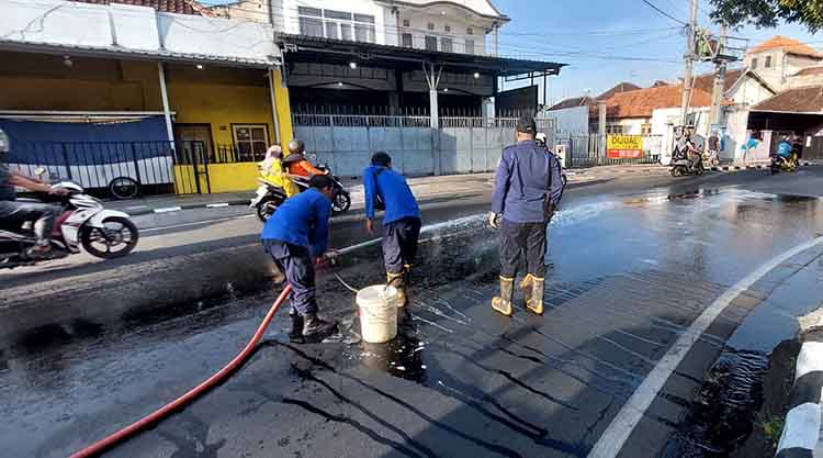 SEMPROT: Tim Damkar Satpol PP Kota Probolinggo membersihkan tumpahan solar di tikungan Palapa Gorden, Jalan Pahlawan, Kota Probolinggo, Sabtu (6/9) pagi.
