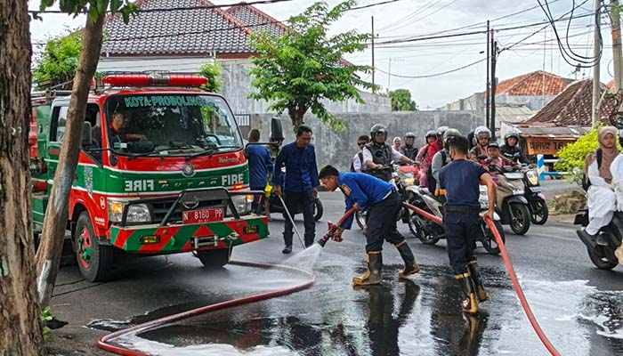 SEMPROT: Petugas Damkar Satpol PP Kota Probolinggo saat menyemprot tumpahan minyak di Jalan Pahlawan, Kelurahan Tisnonegaran, Kecamatan Kanigaran, Kota Probolinggo, Rabu (10/9) pagi