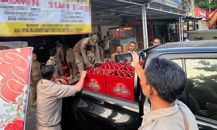 ANGKUT: Petugas Satpol PP Kabupaten Pasuruan saat mengangkut botol-botol miras yang ada di Toko Ultra Pandaan.