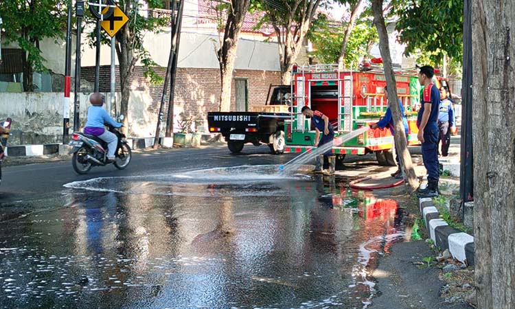 SIRAM: Tim Damkar Satpol PP Kota Probolinggo membersihkan ceceran solar di Jalan Pahlawan, Kota Probolinggo, Rabu (15/10).