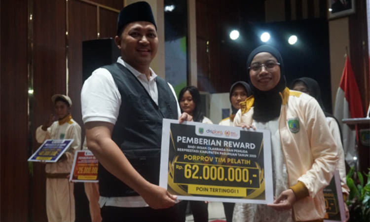 PUNYA PERAN: Bupati Pasuruan Rusdi Sutejo memberikan reward kepada Nadia Kusumawardani (kanan) dari tim pelatih selam.