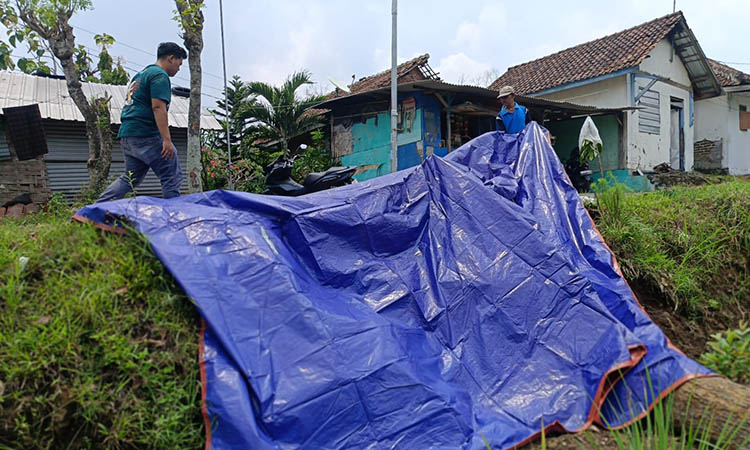 SUDAH DITUTUP: Jalan desa longsor berada di Dusun Betro, Desa Wonosunyo, Kecamatan Gempol di tutup terpal.