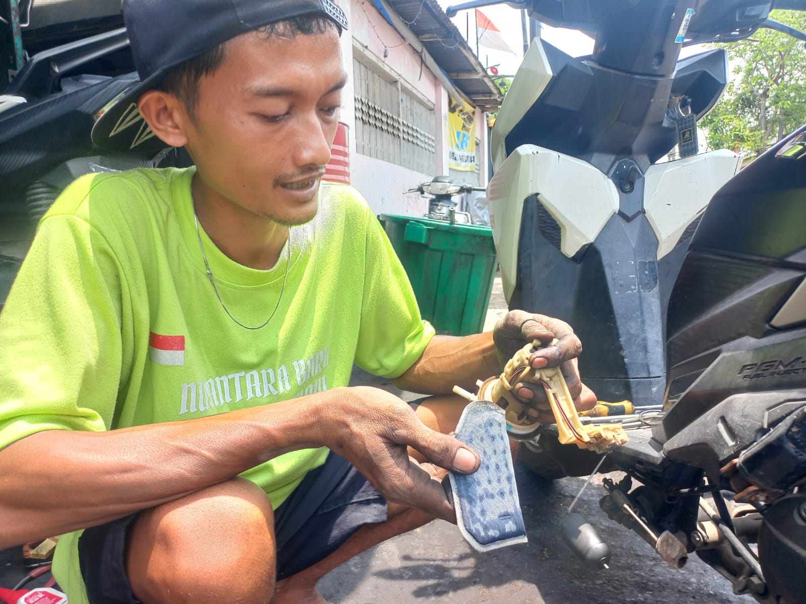 Salah satu montir bengkel di Kota Probolinggo membersihkan filter motor matik pelanggan. Sejak marak kabar motor mbrebet usai isi Pertalite, banyak bengkel kian ramai.