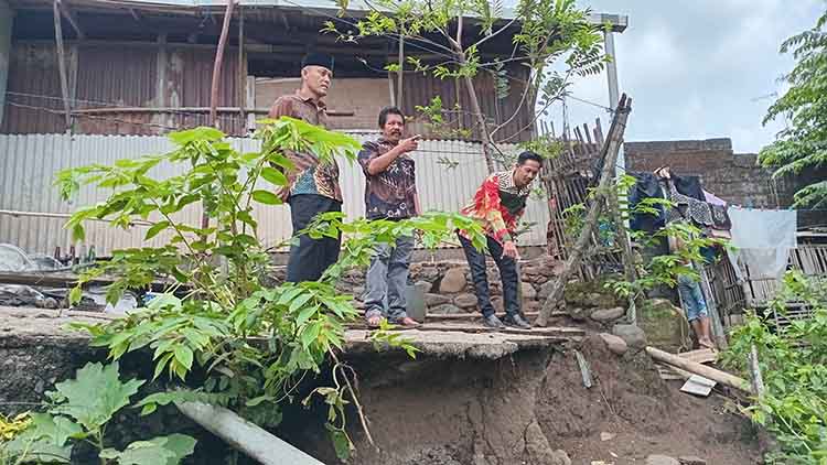 BUTUH BANTUAN: Pj Kepala Desa Karanganyar Edi Kusnanto melihat langsung rumah warga di bibir tanggul bantaran Sungai Karanganyar di Dusun Krajan RT 4/RW 2 yang ambrol terkikis banjir.