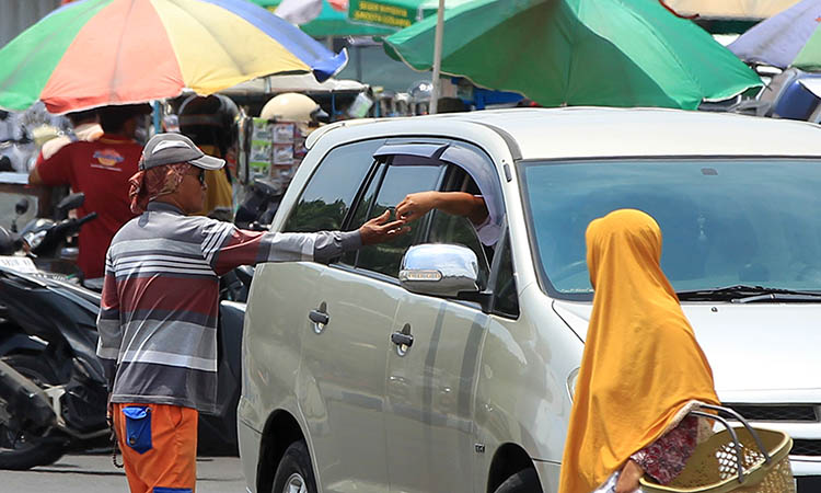 PUNGUT: Seorang jukir di Kota Pasuruan saat memungut parkir ke pengendara. Pihak kepolisian mewanti-wanti jukir agar jujur dalam melaksanakan tugas memungut parkir.