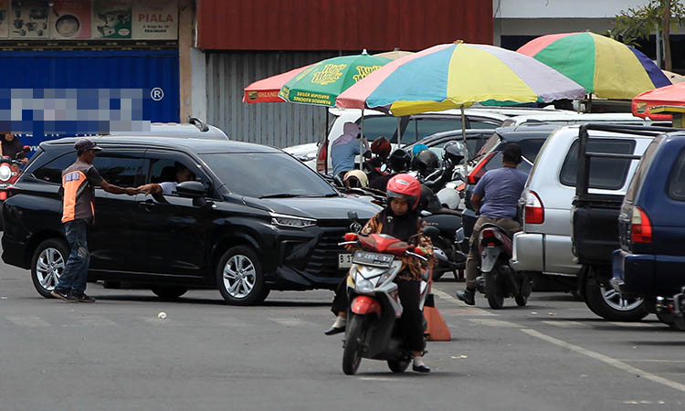 TARIK: Seorang jukir saat melakukan penarikan kepada pengendara. Sejauh ini, setoran parkir ke daerah, masih jauh dari harapan.