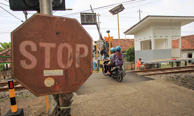 WASPADA: Pengendara motor yang hendak melintas di salah satu perlintasan kereta api. Sejauh ini, belum semua perlintasan di Kabupaten Pasuruan memiliki pos jaga.