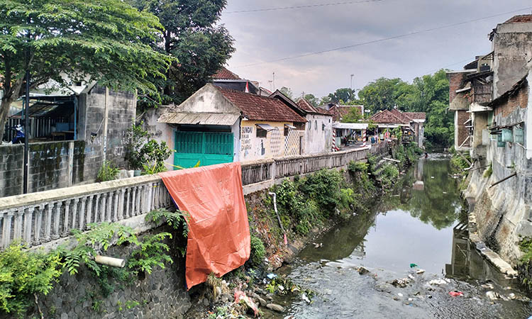 DITUTUPI: Plengsengan Sungai Laban yang ditutupi terpal, usai ambrol. Hal itu dipicu, gerusan air hujan yang mengguyur kawasan setempat, Minggu (9/11) sore.