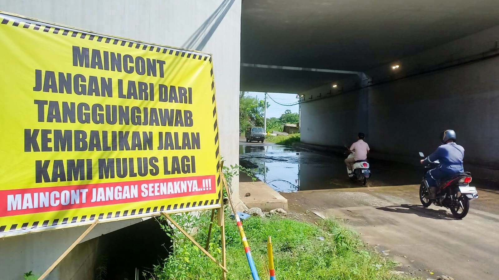 PROTES: Banner protes terlihat dipasang di tepi jalan rusak di bawah Underpass Tol Probowangi paket 3 masuk Sumberanyar, Paiton, Rabu (10/11).