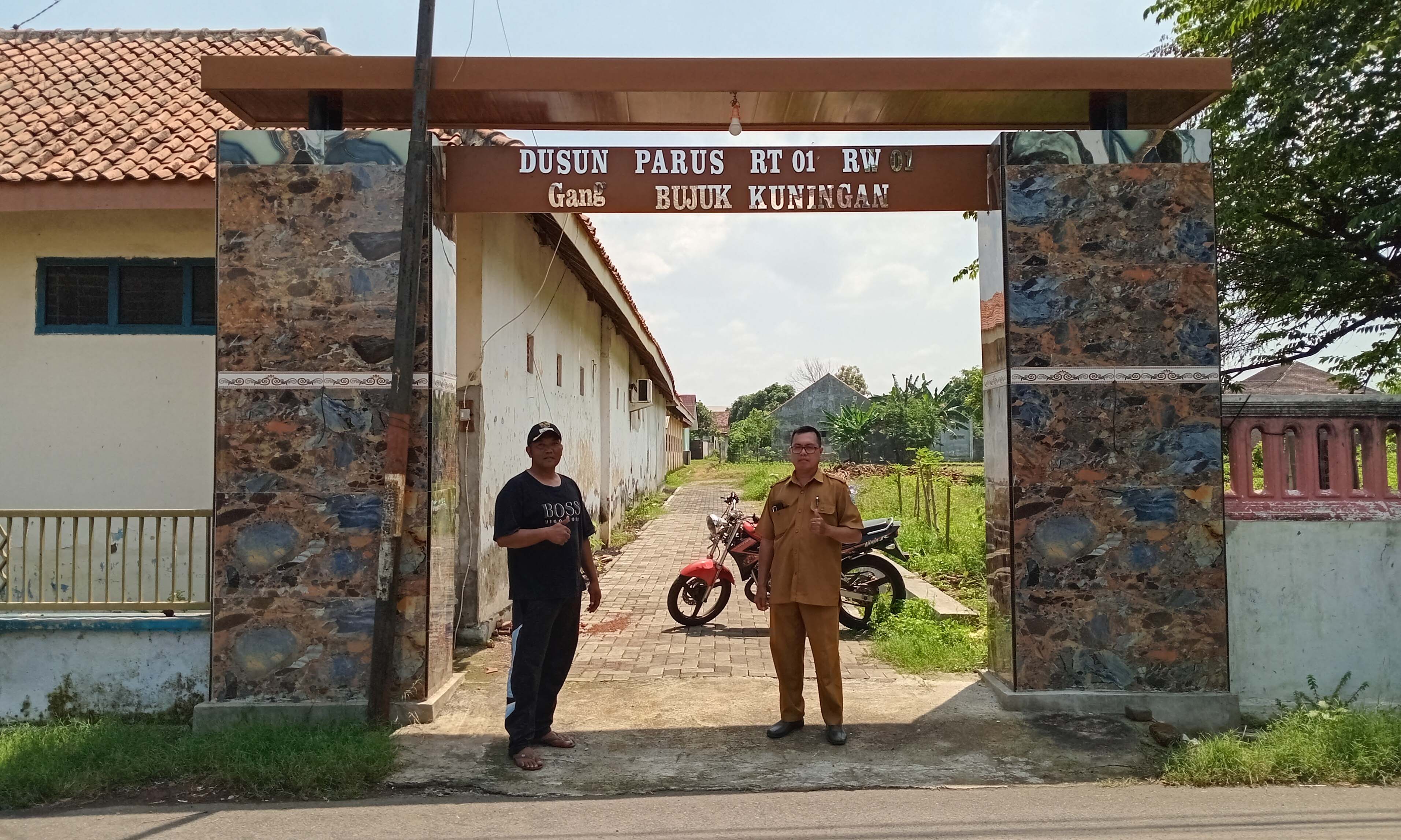 KOKOH: Kepala Desa Lemahkembar Hariyanto (bertopi) bersama Bendahara Desa Salam Cahyono menunjukan gapura desa di Dusun Parus.