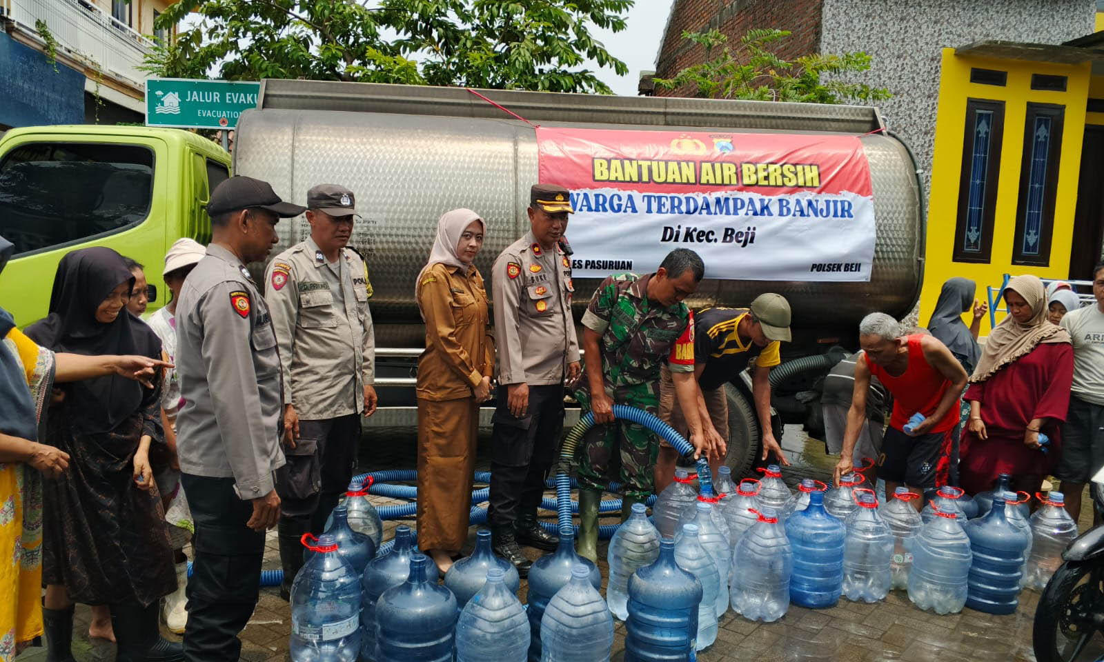 DAMPAK BENCANA: Personel kepolisian dan tentara serta kecamatan membagikan air bersih kepada warga di Kedungringin seusai banjir melanda daerah tersebut, Selasa (25/11)