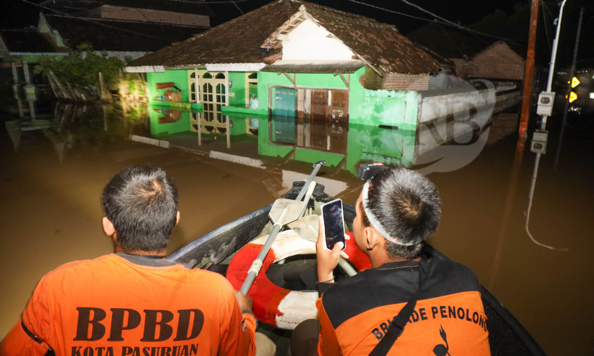 PANTAU KONDISI: Personel BPBD Kota Pasuruan menaiki perahu kerat untuk mengevakuasi warga di Kampung Rujak Gadung, Kelurahan Karangketug, Gadingrejo, yang butuh per