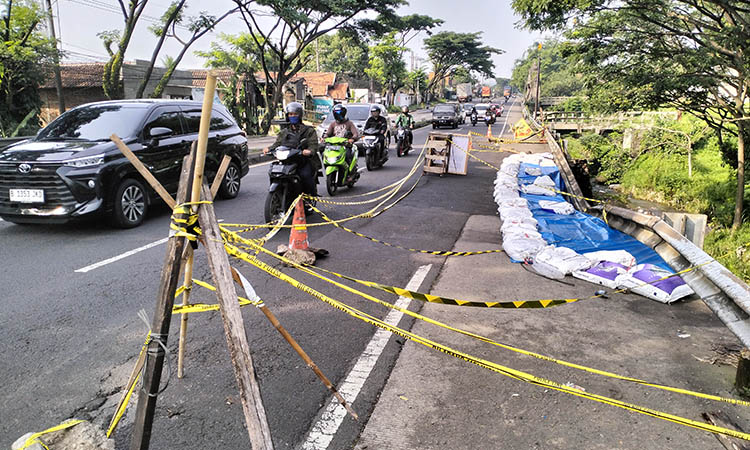 BIAR AMAN: Tepian sungai yang ambrol imbas guyuran hujan deras. Untuk penanganan darurat, pemasangan sanbag dan terpal dilakukan.
