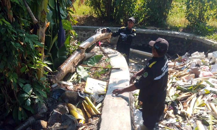 BERSIHKAN: Petugas Dinas PUPR Kota Pasuruan melakukan pembersihan drainase. Hal ini, untuk mengatasi sumbatan air di tengah penghujan.