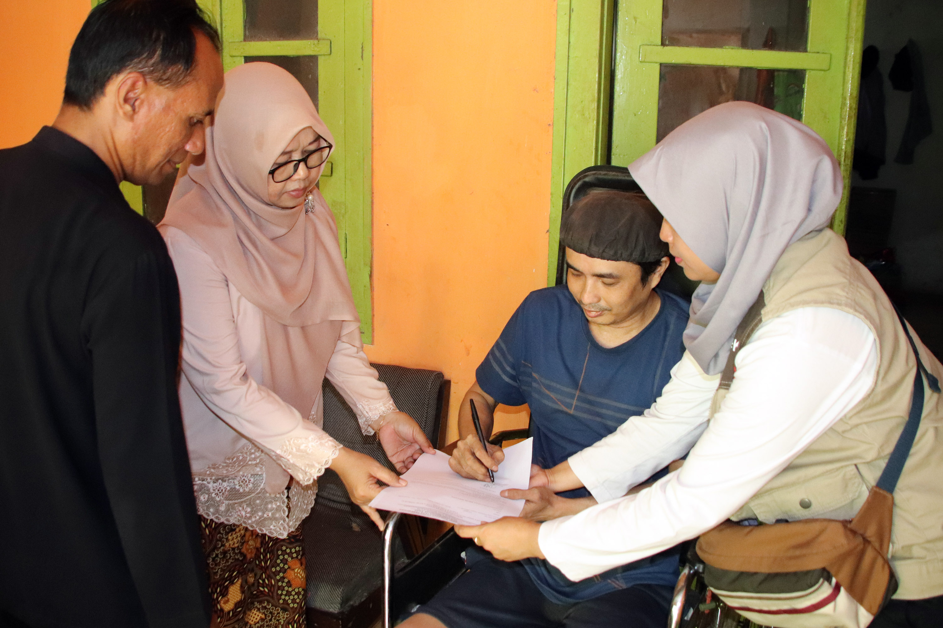 HANTARAN: Salah satu KPM disabilitas wilayah Kedopok semringah tetap mendapatkan BLT-DBHCHT yang diantarkan pegawai Dinsos ke rumahnya, Kamis (4/12).