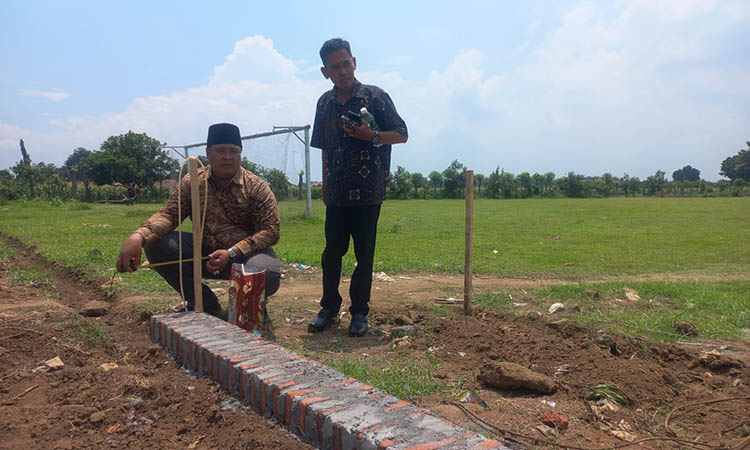 DUKUNG OLAHRAGA: Kepala Desa Kedung Dalem, Sumartono bersama Pendamping Kecamatan Dringu, Ali Sujoko mengecek pengecekan pembangunan pagar di proyek rehabilitasi lapangan sepak bola di Kedung Dalem.