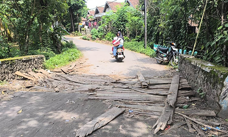 DITUTUPI KAYU: Jalan Kenduruan - Kalisat, di Dusun Montok, Desa Candibinangun, Kecamatan Sukorejo yang jebol sejak awal November 2025. Agar tidak membahayakan, jalan setempat ditutupi dengan kayu.