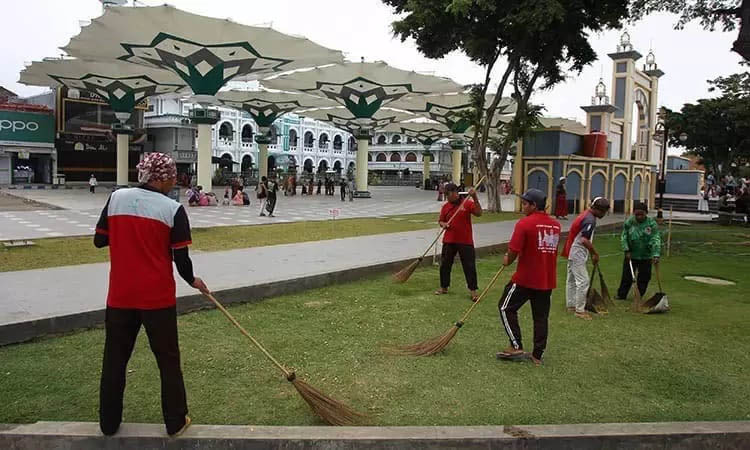 BERSIHKAN: Sejumlah petugas kebersihan saat membersihkan kawasan Alun-Alun Kota Pasuruan.