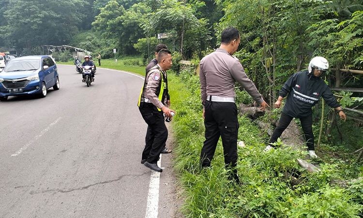 LOKASI KEJADIAN: Personel Satlantas Polres Pasuruan menggelar olah TKP di Jalan raya Gempol tepatnya di tikungan Watukosek yang menjadi lokasi premotor terjatuh.